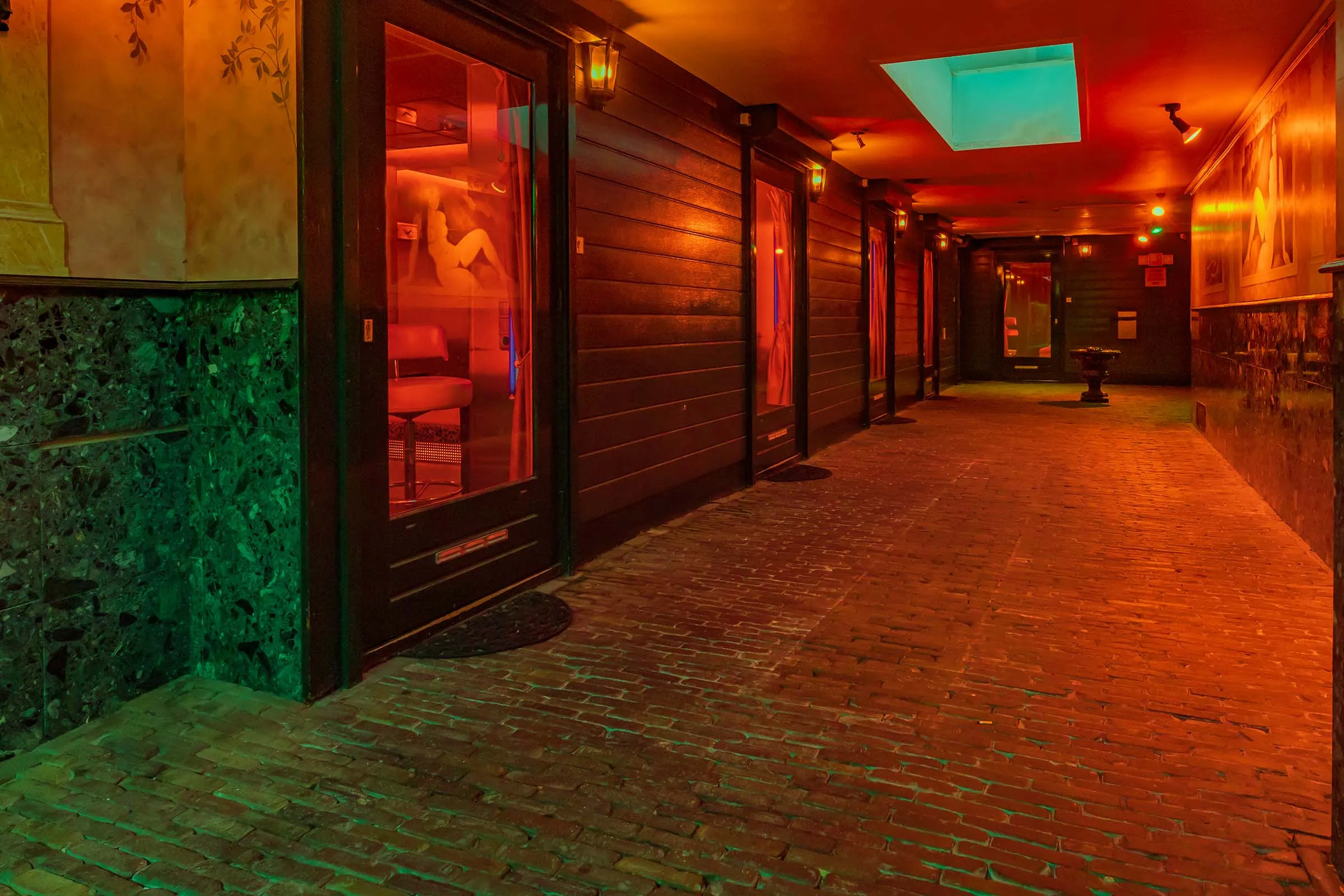 De overdekte gang langs de kamers, in warm licht, met de deuren op een rij.