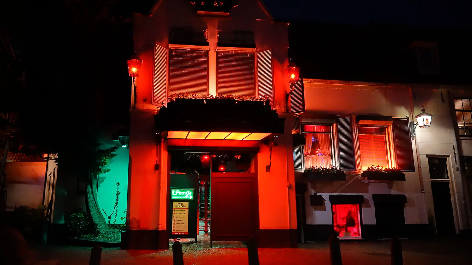Warm verlichte doorgang naar het besloten hofje van ’t Poortje, gezien vanaf de straat.