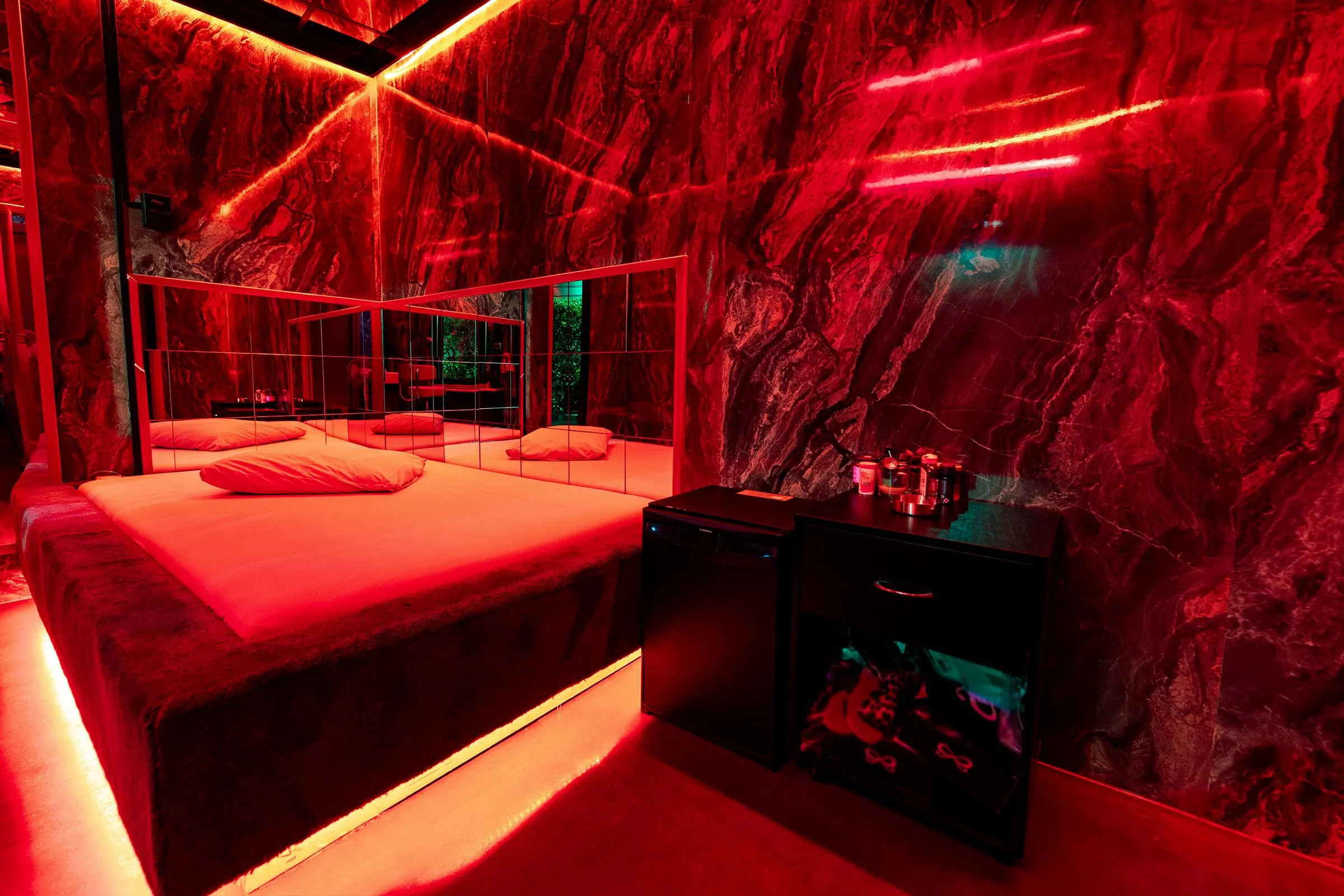 Een opgemaakte kamer met eigen douche, in rood licht.